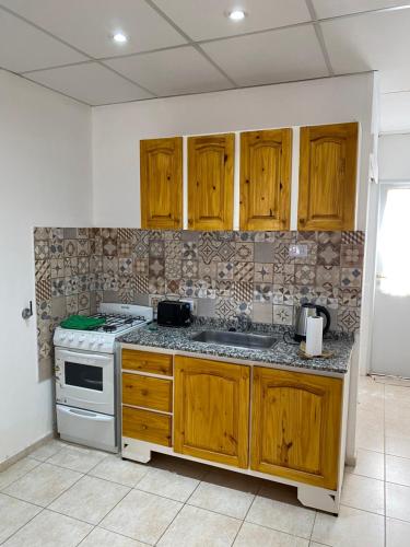 a kitchen with wooden cabinets and a stove at Departamento Navarro 2 in Malargüe