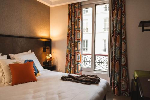 um quarto com uma cama e uma grande janela em La Maison Montparnasse em Paris