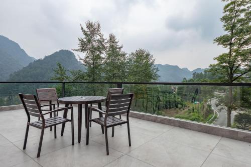 a table and chairs on a balcony with a view at Zhangjiajie Qiquan Vacation B&B in Zhangjiajie