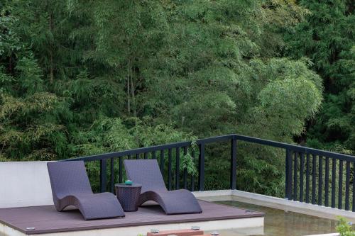 two chairs sitting on a table on a balcony at Zhangjiajie Qiquan Vacation B&B in Zhangjiajie