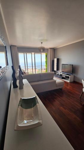 - un salon avec un canapé et une télévision dans l'établissement Seaview Relax Apartment, à Caniço