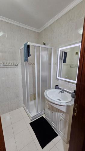 a white bathroom with a shower and a sink at Seaview Relax Apartment in Caniço
