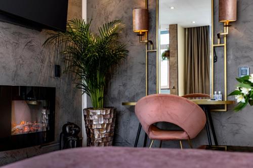 a dining room with a pink chair and a fireplace at Jupiter Hotel in Amsterdam