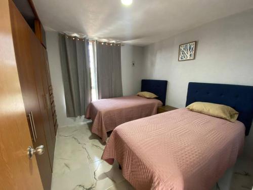 Habitación con 2 camas con sábanas rosas y ventana. en Casa duplex aeropuerto/arena VFG, en Guadalajara