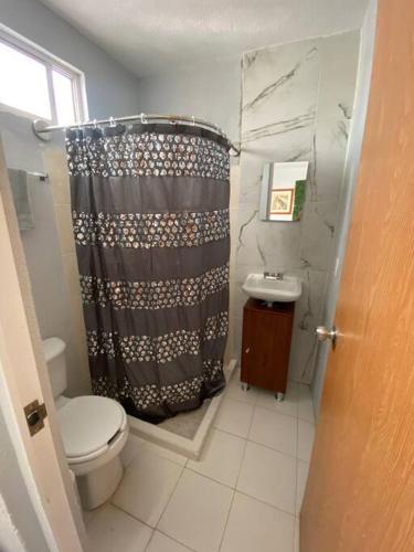 a bathroom with a shower curtain and a toilet at Casa duplex aeropuerto/arena VFG in Guadalajara