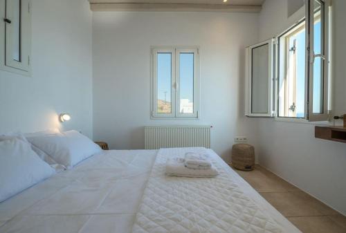 a white bedroom with a large bed with two towels on it at La Chapelle Ouest & Grand suite in Agios Romanos