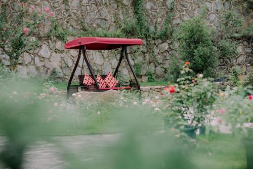 a red bird feeder in a garden with flowers at Zhangjiajie Qiquan Vacation B&B in Zhangjiajie