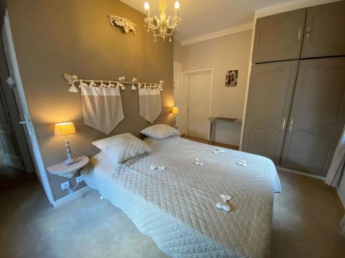 Un dormitorio con una cama con sábanas blancas y una lámpara de araña. en Chambres d'Hôtes La Petite Boynarde, en Rivière-sur-Tarn