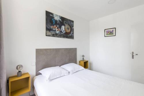 a bedroom with a white bed and a picture on the wall at Vinaura - Appartement élégant avec parking in Reims
