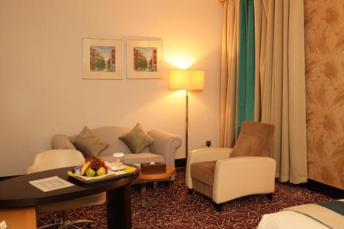 a hotel room with a couch and a table and chairs at Golden Tulip Hail in Hail