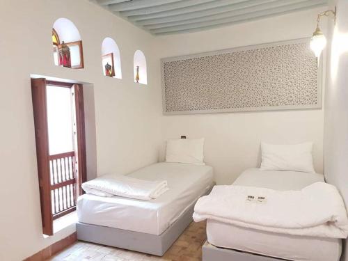 Duas camas num quarto branco com uma janela em Entire Private House in Fez Medina! em Fez