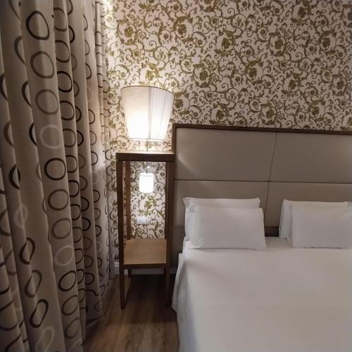 a bedroom with two beds and a wall with floral wallpaper at Hotel Montreal in Florence