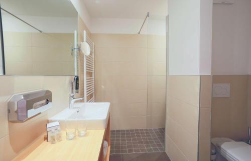 a bathroom with a sink and a mirror and a toilet at Hotel Bergkristall in Mallnitz
