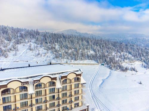 a hotel in the snow with a mountain at Elena Spa Resort in Bukovel