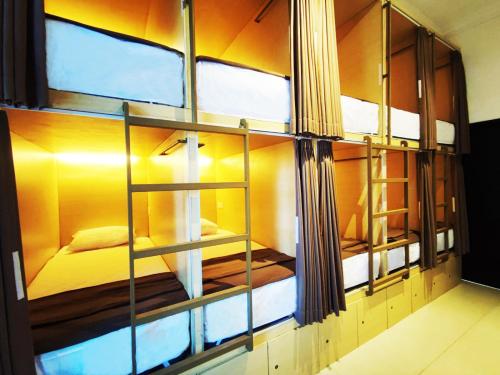 a room with a glass wall with a bed in it at Fora Capsule Hostel Tuban Kuta Bali in Kuta