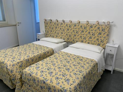 twee bedden in een kamer met gele en blauwe lakens bij B&B Lidia Ricci in Montegiorgio