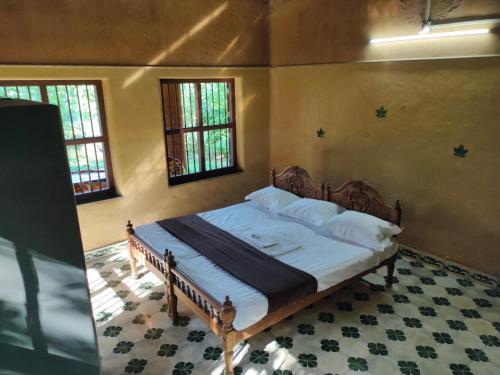 een slaapkamer met een bed in een kamer met ramen bij Chithira Homestay (Kerala traditional mud house) in Kodali