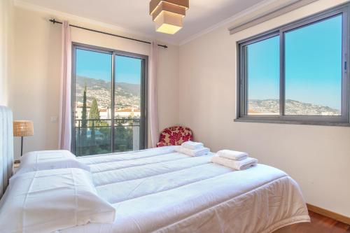 een witte slaapkamer met 2 bedden en 2 ramen bij Barreiros Residence View in Funchal