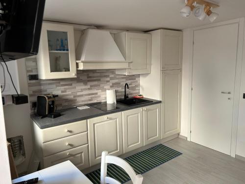 una cocina con armarios blancos y fregadero en Casa Martino, en Norcia