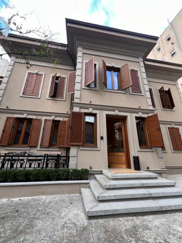Casa blanca con persianas marrones y escaleras en Faces & Places Boutique Hotel, en Tirana