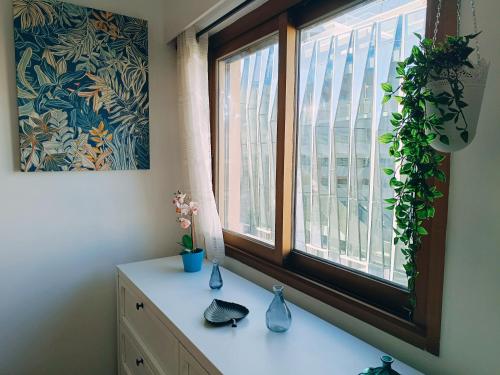 Cette chambre dispose d'une fenêtre avec un vase sur une commode. dans l'établissement 2 pièces climatisé avec balcon dans le vieil Antibes, résidence avec ascenseur, à Antibes