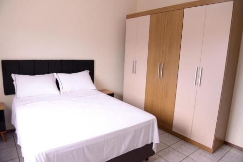 a bedroom with a white bed and a wooden cabinet at Incrivel apto completo e confortavel Santa Rosa RS in Santa Rosa