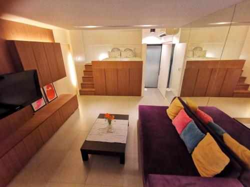 a living room with a purple couch and a coffee table at Tower Resident in the Heart of Bangkok Shopping Center in Makkasan