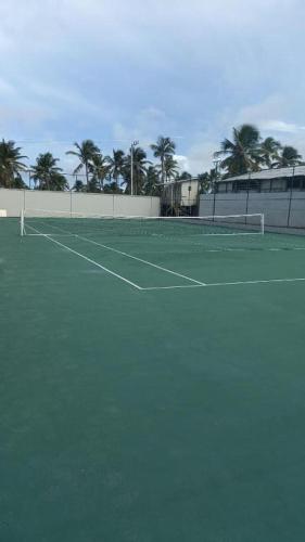 a tennis court with palm trees in the background at Salinas Premium resort in Salinópolis