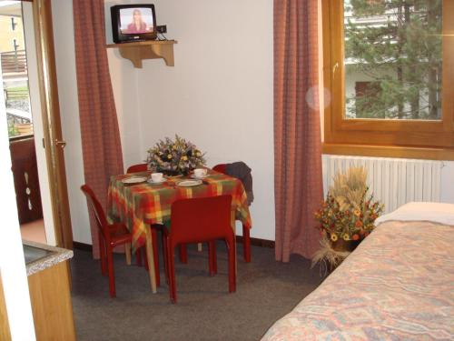 una habitación con una mesa con sillas y una mesa y una habitación con una cama en Hotel Derby, en Bormio