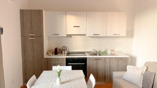 een keuken met een tafel en een keuken met witte kasten bij Confortevole Appartamento con Piscina in Castiglione del Lago