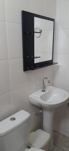 a bathroom with a sink and a toilet and a mirror at Quartos Residencial Arcos in Arcos