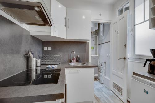 a kitchen with white cabinets and a sink at Smart apart in Paris in Vanves