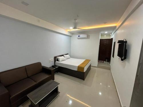 Habitación pequeña con cama y sofá en Hotel Pleasure, en Surat