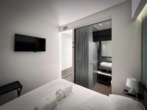 a white bedroom with a bed and a television at Mutina Suites in Modena