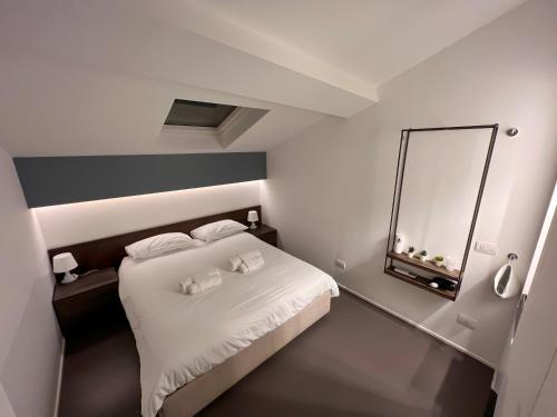 a bedroom with a white bed and a mirror at Mutina Suites in Modena