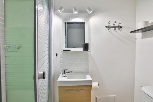 une salle de bain blanche avec un lavabo et un miroir dans l'établissement Le Victor Hugo #Hypercentre #Netflix, à Cognac