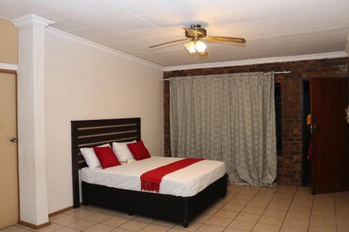 a bedroom with a bed with red pillows and a ceiling fan at GLESTER GUEST HOUSE in Pretoria