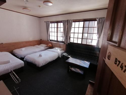 a room with three beds and two windows at Pilot Lodge in Hakuba