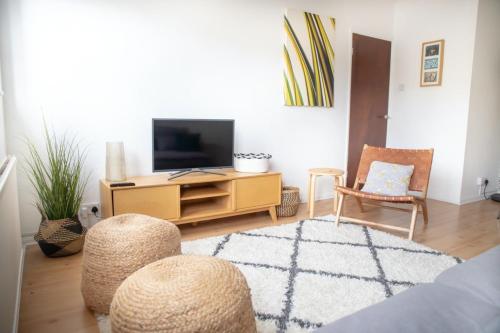 uma sala de estar com uma televisão de ecrã plano e cadeiras em GuestReady - Homely Leeds City Apartment Sleep 4 em Meanwood