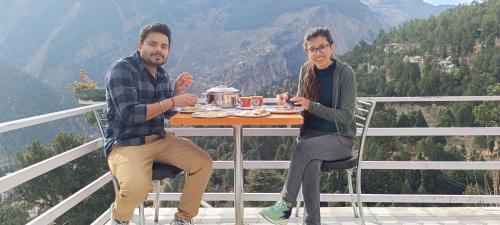 a man and a woman sitting at a table eating food at Kin Vatika Homestay in Kalpa
