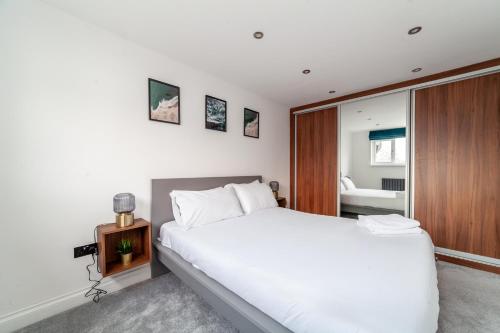 een slaapkamer met een groot wit bed en een spiegel bij Home from Home in Londen