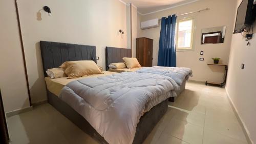 - 2 lits jumeaux dans une chambre avec des rideaux bleus dans l'établissement Pyramids Road, au Caire