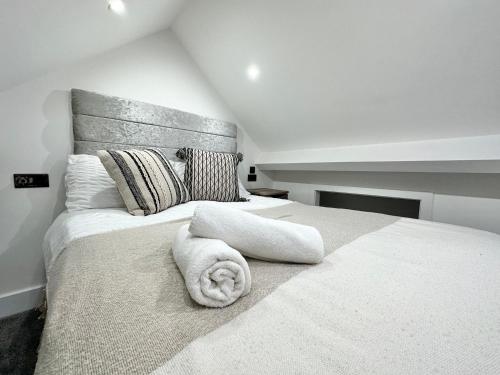 a bedroom with a large white bed with towels on it at Luxury Duplex City Centre Apartment in Leeds