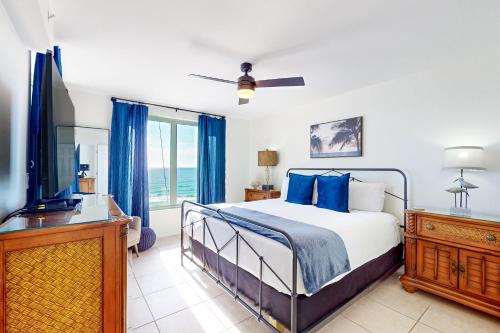 a bedroom with a bed with blue pillows and a television at Island Princess 704 in Fort Walton Beach
