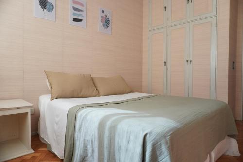 una camera da letto con un letto con lenzuola bianche e quadri appesi al muro di M Pugliese Amplio, cómodo y luminoso a metros del subte a Buenos Aires