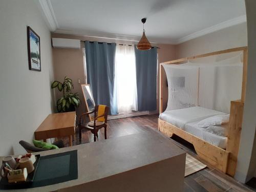 um quarto com uma cama, uma secretária e uma mesa em La Villa d'O em Toubab Dialaw