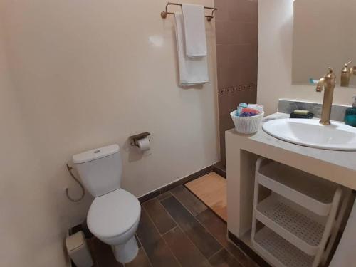 a bathroom with a white toilet and a sink at La Villa d'O in Toubab Dialaw