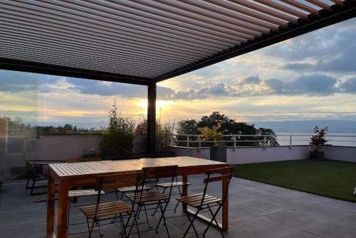 IMMODREAMS - L'Attik with lake views and 80m2 terrace في إيفيان لي بان: فناء على طاولة وكراسي خشبية على السطح