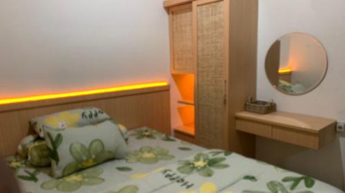 een kleine slaapkamer met een bed met een spiegel en een wastafel bij AdyneVille in Blimbing
