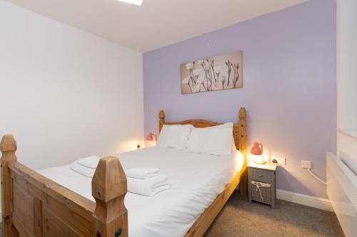 - une chambre avec un lit en bois et des draps blancs dans l'établissement Cosy 2BR Apartment in Nottingham, à Nottingham